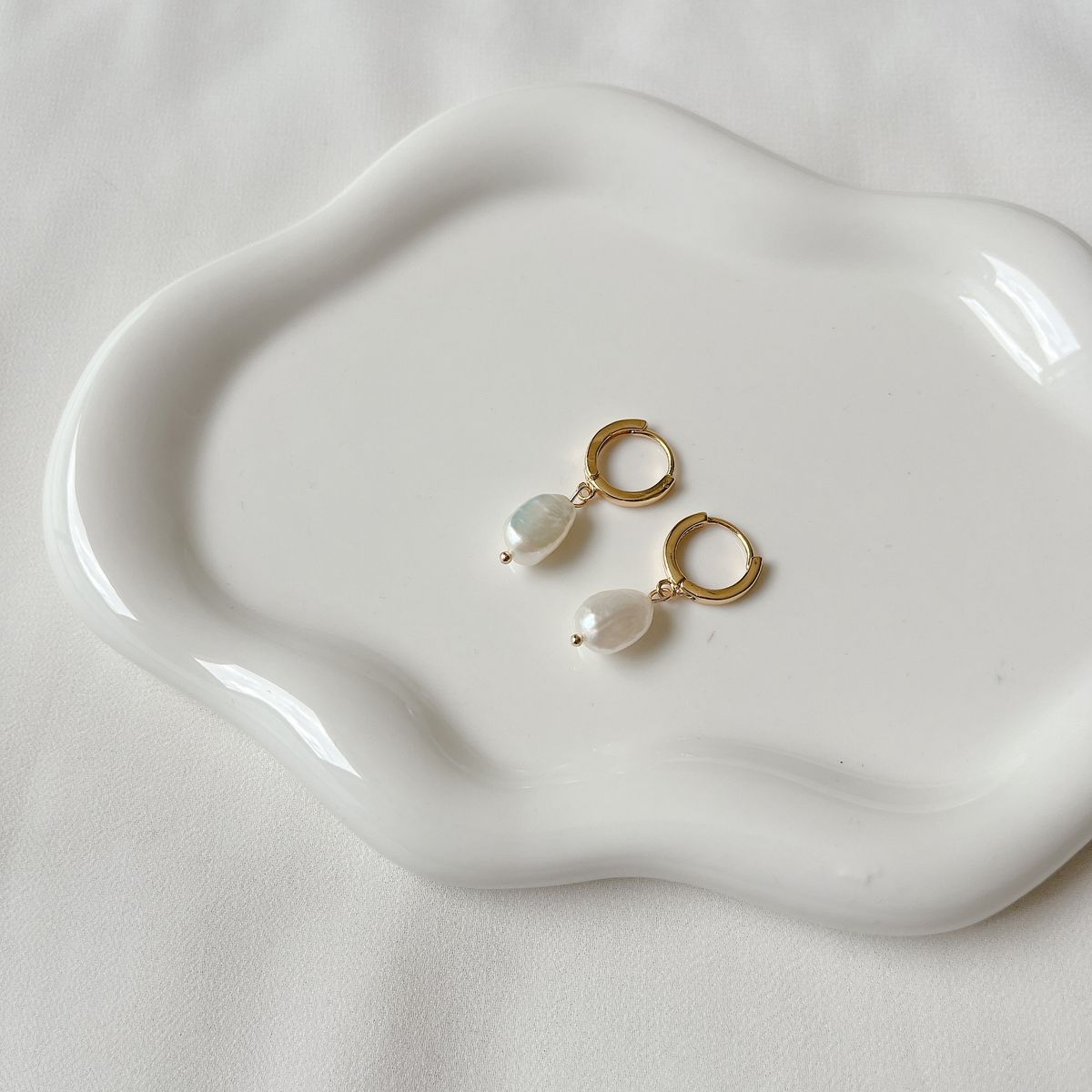 Pearl earrings resting on a ceramic dish